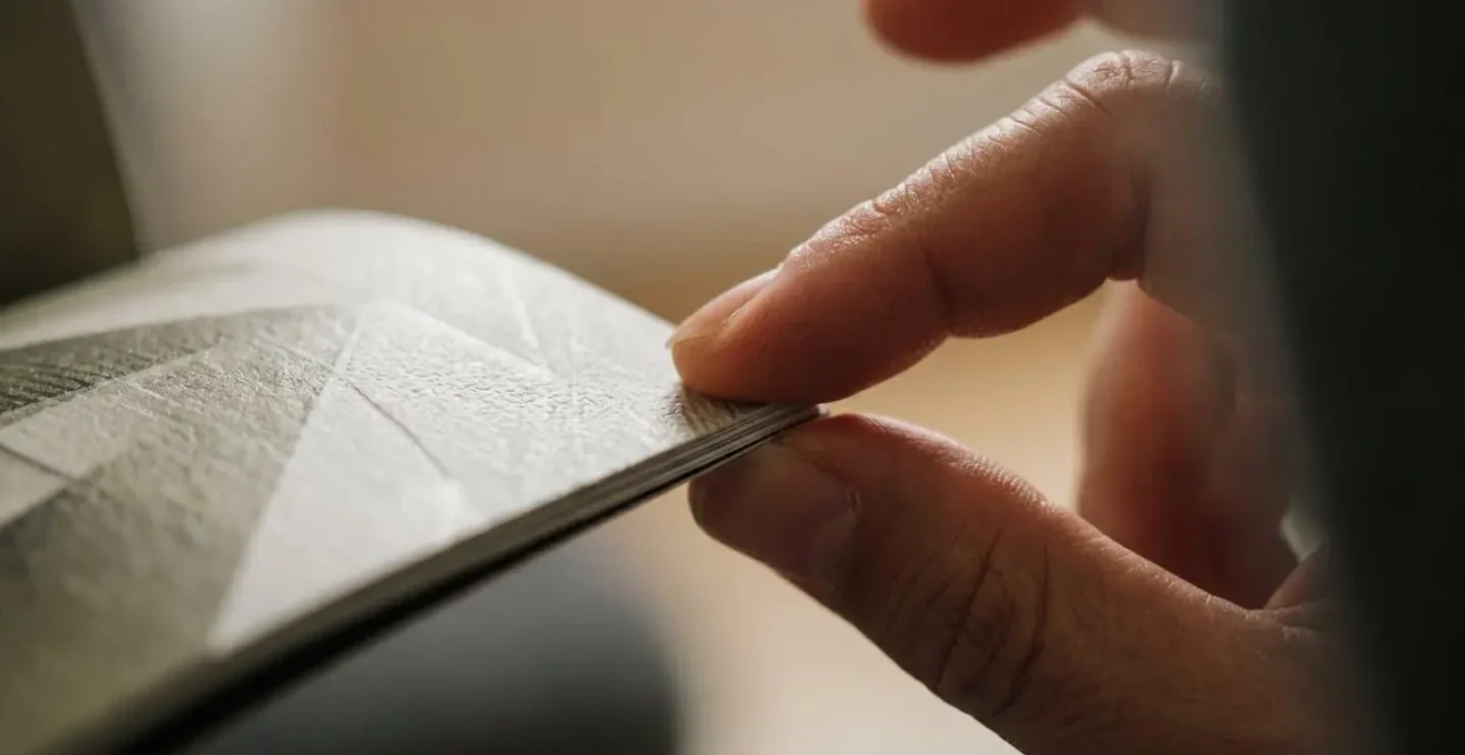 Gros plan sur des mains évaluant le poids et la texture d'un catalogue papier premium